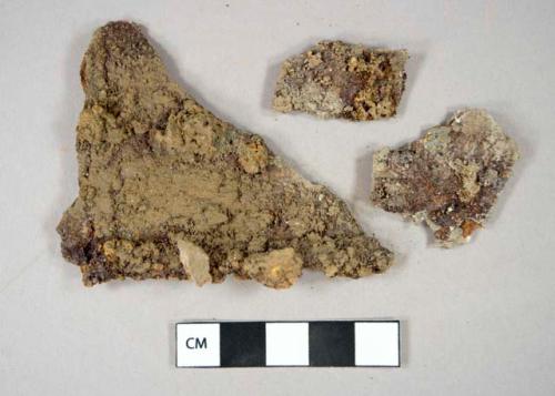 Metal, sheet, oxidized fragments with stone adhesions