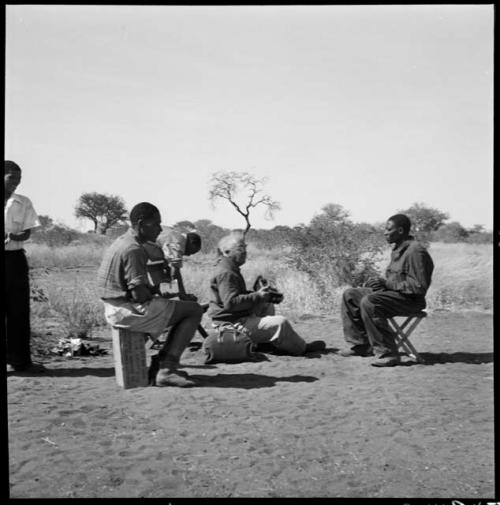 Laurence Marshall sitting in camp with expedition staff members