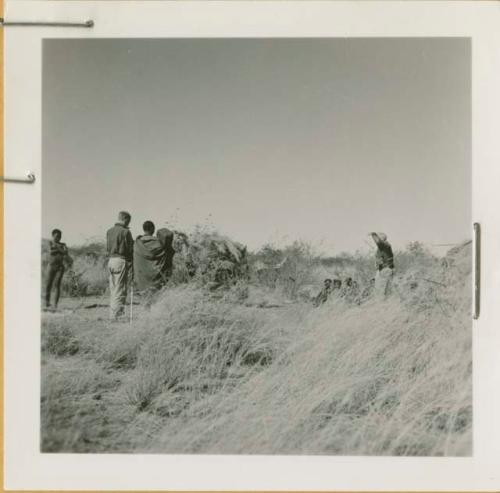 Group of people sitting in grass, with John Marshall filming them