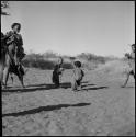 Women playing a singing game, with children imitating them