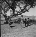 Children playing under a tree with a swing they made from leather