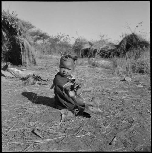 Khuan//a (daughter of //Ao and ≠Nisa) sitting, wearing ornaments in her hair and a little kaross