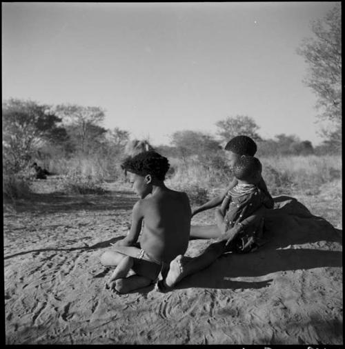 Boys sitting on an anthill, in late afternoon light