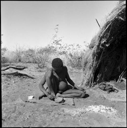 Man sitting in front of a skerm smoothing something, possibly an arrow foreshaft