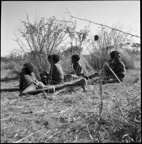 Boys sitting at the edge of the cleared patch, watching girls dance