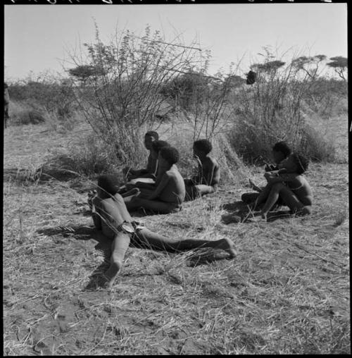 Boys sitting at the edge of the cleared patch, watching girls dance