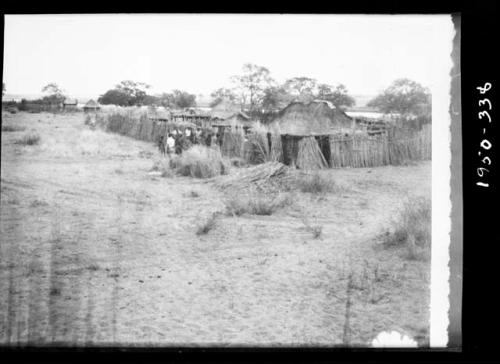 Group of people standing next to a fence surrounding a village