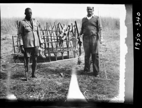 Two men standing next to a "sled"