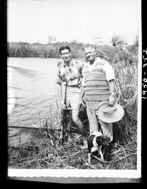 Assistant Manager of WNLA (Witwatersrand Native Labor Association) (left) standing with another man and a dog next to the Okavango River