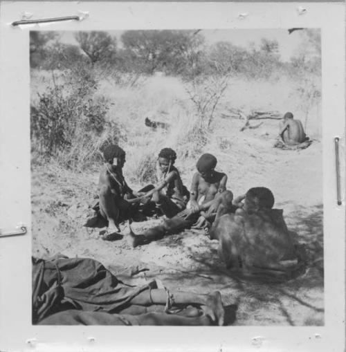 /Naoka (first wife of /Ti!kay) performs a choa ceremony for her daughter, Bau (wife of Tsamgao); N!ai (/Naoka's sister), !Ghia (wife of ≠Gao) and Goishay (mother of /Naoka and N!ai) are sitting with their backs to the camera watching