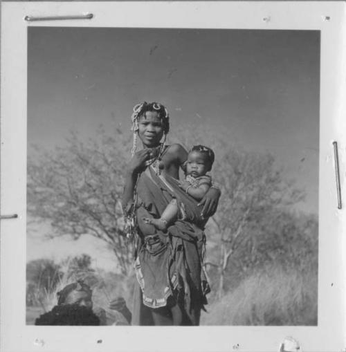 Woman from /Ti!kay's group standing and carrying her baby