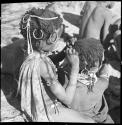 Girl looking for lice in the hair of a smaller child