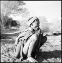 /Naoka (wife of "Gao Medicine") wearing an ostrich eggshell headband, squatting