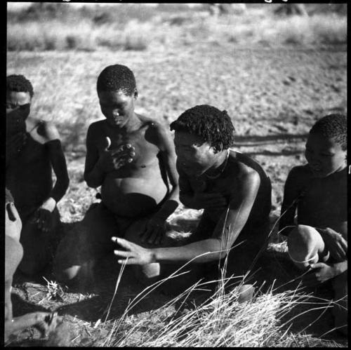 Men and boys playing !ó'm!hú / !’Om g!xuni / ’Ai kota !U!u g!xuni / N!aih //’an (the porcupine game, also known as the axe game, assegai game or war game), including //Ao (husband of Khuan//a, daughter of /Gaishay of Band 4), who is stretching out his hand (print is a cropped image)