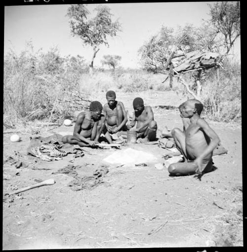 Group of men sitting around a fire, talking and working, including "Old Gau" (Band 1), ≠Gao (husband of Khwo//o-/Gasa and brother of "Old Gau"), /Gaishay, and "Qui /Navel"