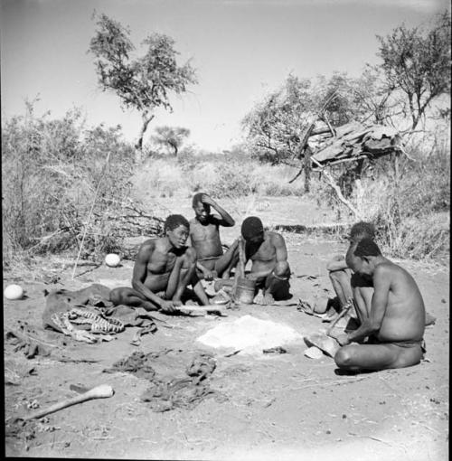 Group of men sitting around a fire, talking and working, including "Old Gau" (Band 1), ≠Gao (husband of Khwo//o-/Gasa and brother of "Old Gau"), /Gaishay, and "Qui /Navel"