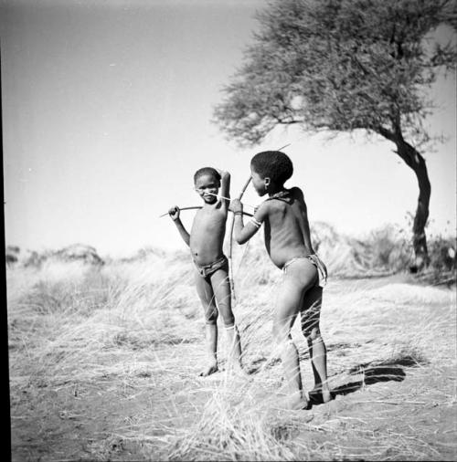 Two boys standing and holding bows and arrows