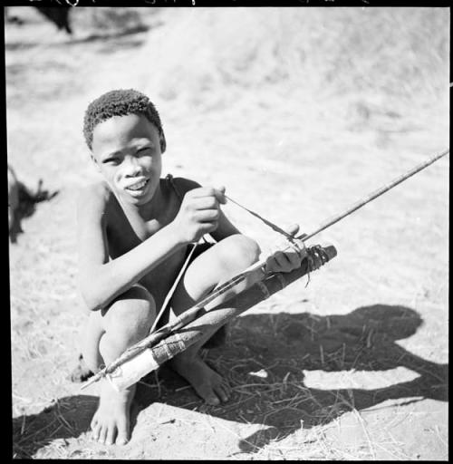 /Gishay (son of "Old Gau") squatting and holding a quiver and bow