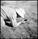 Laurence Marshall kneeling on the ground and holding a camera lens