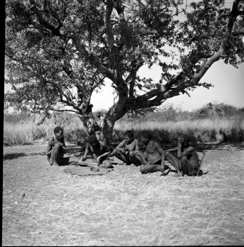 Man throwing oracle disks, and a group of men sitting and watching him