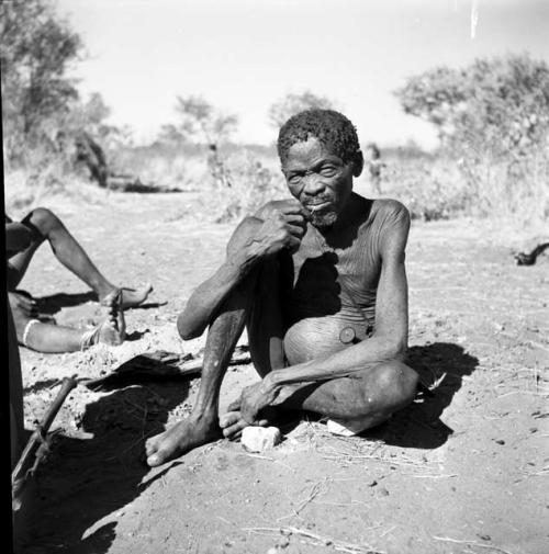 Man sitting and resting his leg on a stone, possibly Gao of Band 10 or //Ao