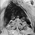 /Goishay (wife of ≠Gao, headman of Band 3) sitting with two of her children in front of a skerm