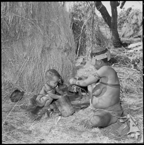 //Kushay ("Gao Helmet's" second wife) and Xama (her little daughter) playing with the mortar, sitting beside their skerm