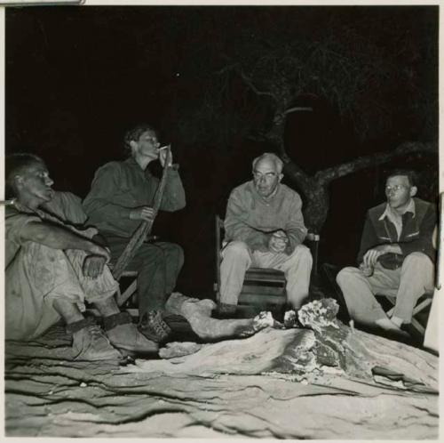 John Marshall, Lorna Marshall, Laurence Marshall, and Ernst Westphal sitting around the fire