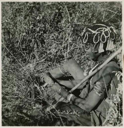 Woman holding veldkos, sitting next to the hole she dug it out of