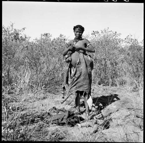 Woman tying her kaross to make pouch for carrying veldkos