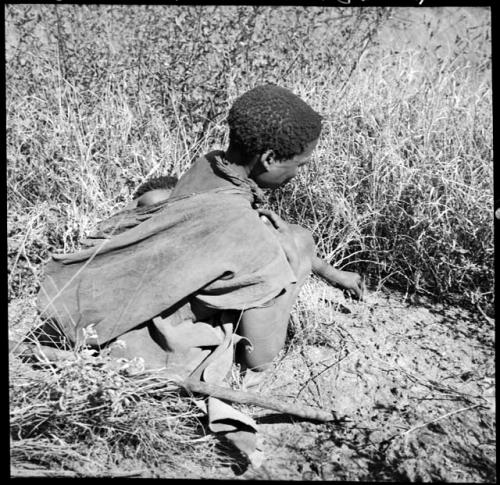 Woman holding the stem of an edible root, picking it out from the grass