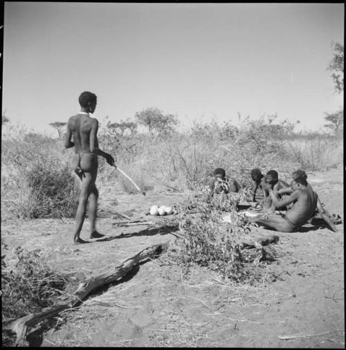 "Old ≠Toma" of Band 2, ≠Gao (husband of Khwo//o-/Gasa, brother of "Old Gau") of Band 4, "Old /Gaishay" of Band 3 and "/Qui Navel" of Band 1 sitting with "Old Gau" around the ashes of his fire, with Gao of Band 2 approaching them