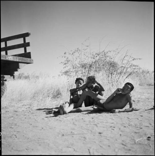 Group of boys sitting on the ground near the back of an expedition truck