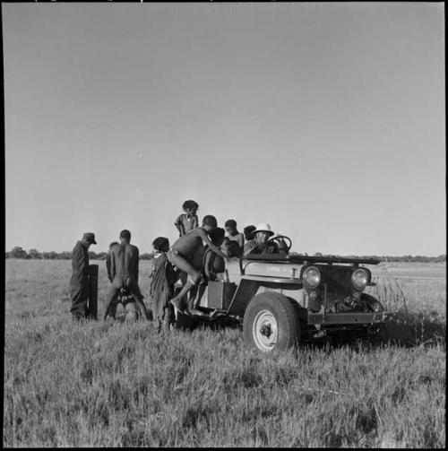 Children climbing into the expedition Jeep with Laurence Marshall, Ngani standing near them