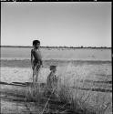 Two girls, one standing, one sitting, at the edge of the pan