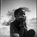 Boy sitting, with his hands on his cheeks