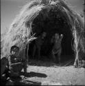 Child sitting next to a skerm, with two children standing inside it