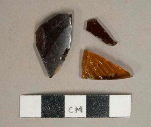 Amber glass vessel fragments, 1 fragment with embossed lettering