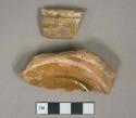 Brown lead glazed redware vessel base and handle fragments, slip decorated with slip missing
