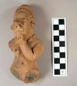 Upper part of pottery figurine -- one arm broken and one hand on jaw