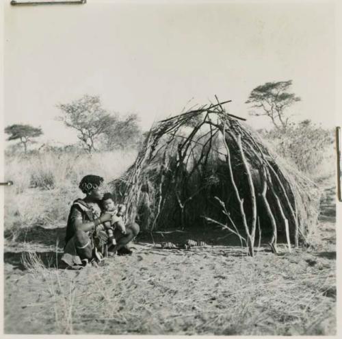 Woman holding a baby, sitting next to a skerm