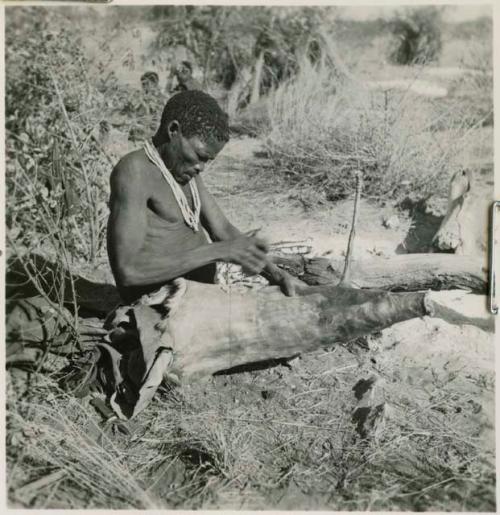 Man making a bag from the whole skin of a wild pig