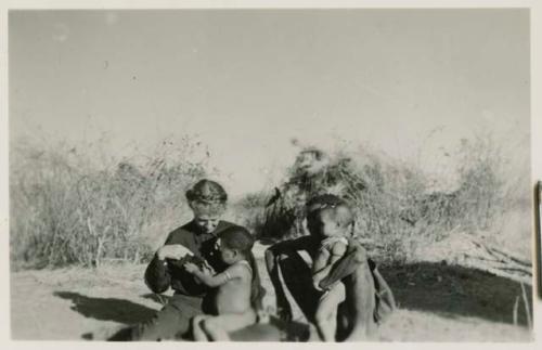 Gau sitting with Lorna Marshall, with /Qui sitting in Lorna's lap and Khuan//a leaning against Gau