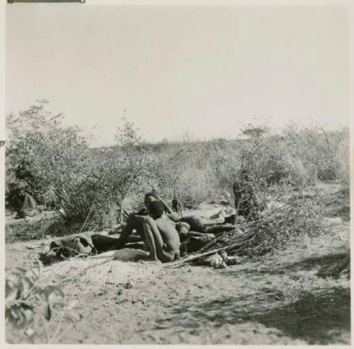 Group of boys sitting and lying down near a bed of ashes in their dwelling place