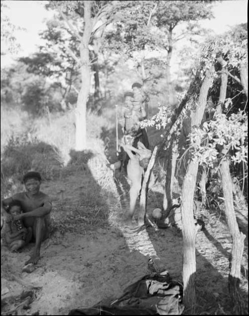 Group of people sitting next to a skerm built with heavy structure and leafy branches