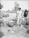 WNLA (Witwatersrand Native Labor Association) convoy cook standing next to a cauldron of mealie porridge