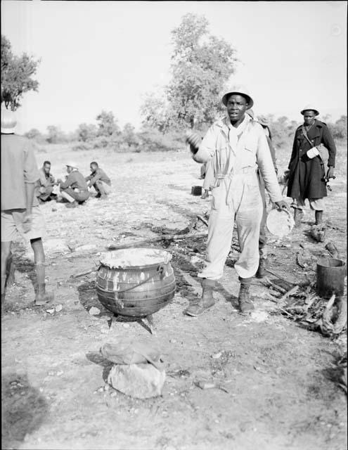 WNLA (Witwatersrand Native Labor Association) convoy cook standing next to a cauldron of mealie porridge