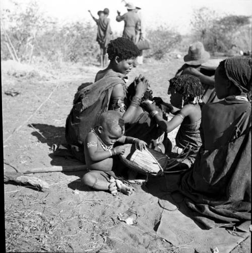 //Khuana looking for lice on her child's head, N!ai looking for lice in the child's beads, and /Gaishay (son of Gao and Di!ai) examining a //guashi