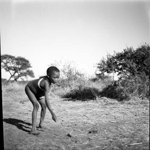 Boy picking up a djani (winged toy made from a hollow reed) with his stick