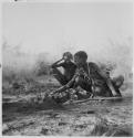 "Old /Gasa" cooking a wildebeest head, with her grandson ≠Toma (son of Gau) watching her